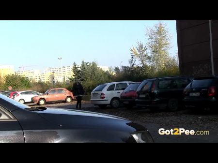 Hocke zwischen geparkten Autos, um in der Öffentlichkeit zu pissen 